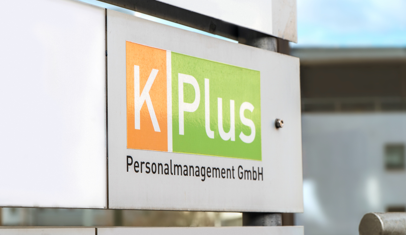Schild mit K-Plus Logo vor Gebäude