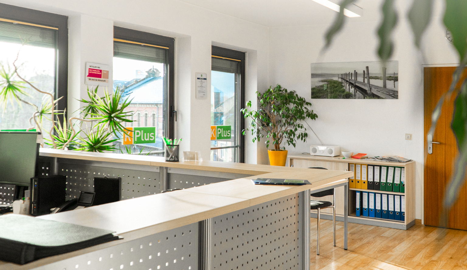Büro von K-Plus Personalmanagement: Empfang mit Besprechungstisch und Regal mit Ordnern vor Fensterfront