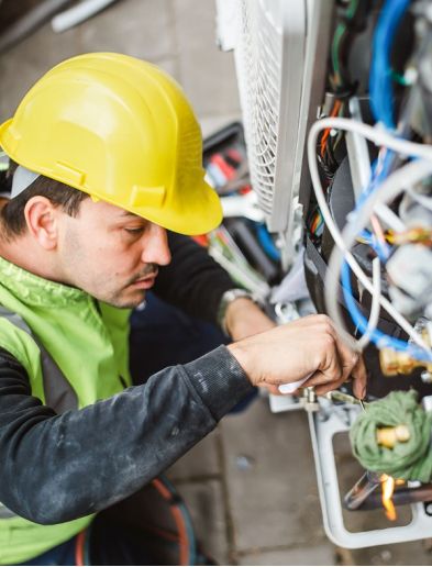 Job bei K-Plus Personalmanagement: Elektriker arbeitet an Kabeln