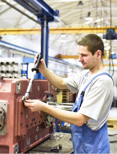 Job bei K-Plus Personalmanagement: Industriemechaniker schraubt an Maschine