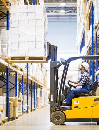 Job bei K-Plus Personalmanagement: Staplerfahrer hebt Palette mit Kartons aus Hochregal