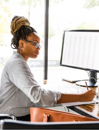 Job bei K-Plus Personalmanagement: Datenerfasserin am Schreibtisch vor Tabelle und Ordner